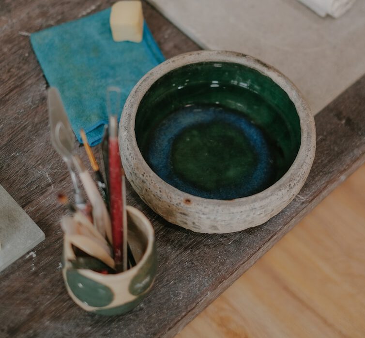 a wooden table topped with a green bowl filled with paint
