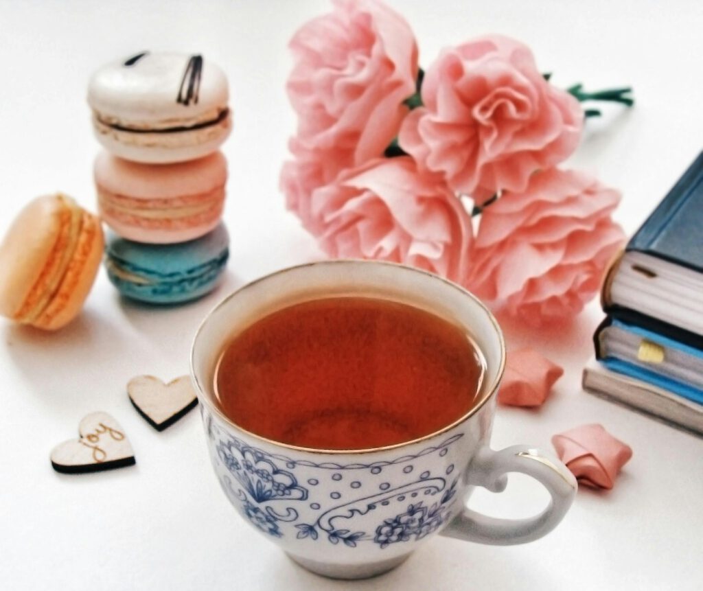 Cup of tea with macarons and pink flowers